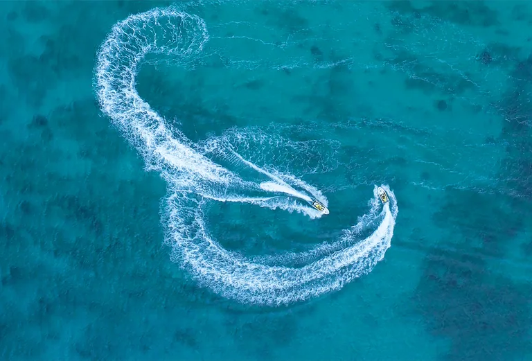 Vue drone de jet skis traçant des courbes sur l'eau turquoise